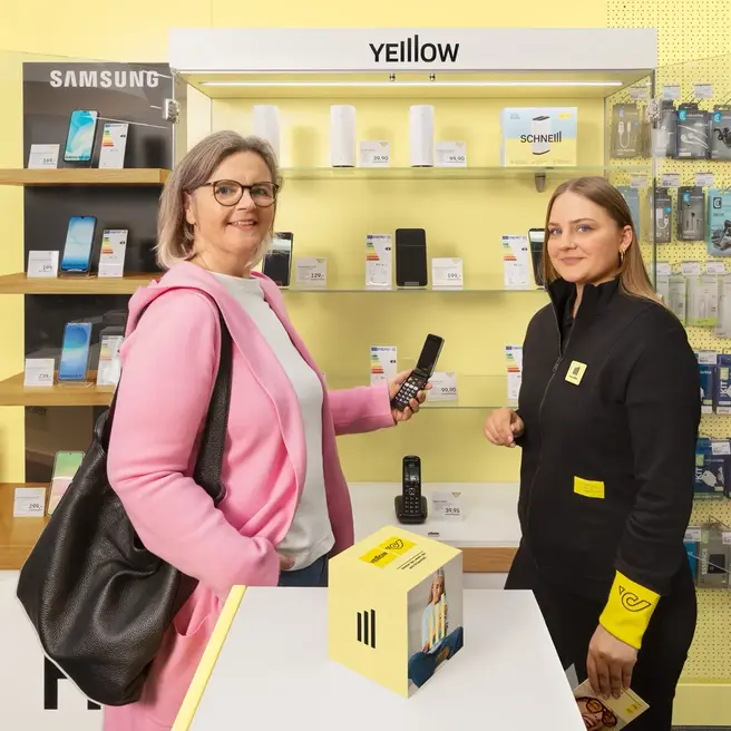 Eine Person steht im Schalter Bereich mit ihrem Smartphone.