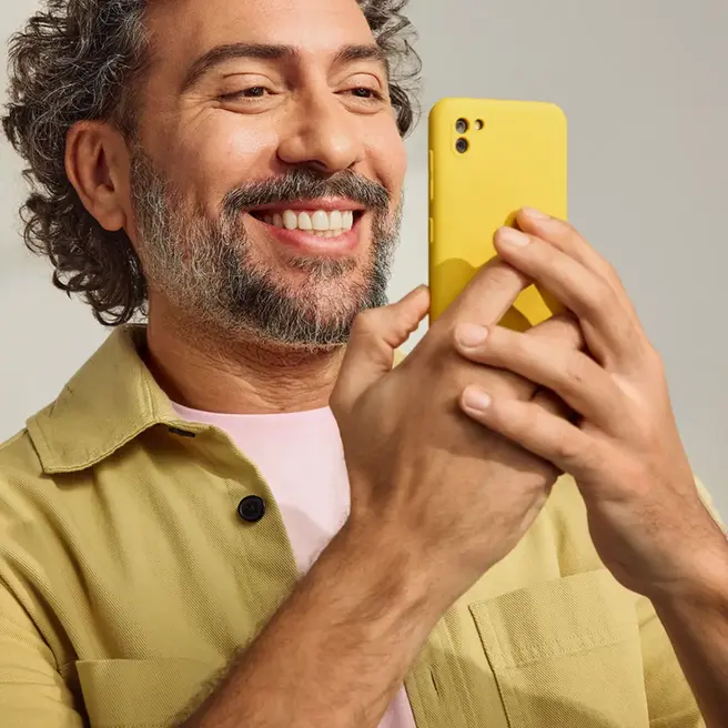 Fr&ouml;hlicher Mann mit gelbem Smartphone in der Hand